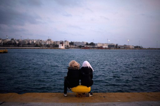 Two women from Syria sit facing the sea in Athens in March 2016. AFP/Angelos Tzortzinis