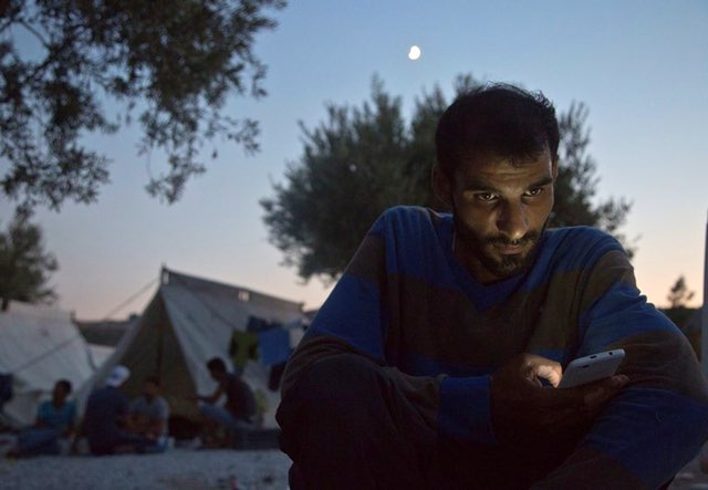 A Syrian man looks at his cellphone in the Kara Tepe refugee camp on the Greek island of Lesbos, August 20, 2015. AP/Visar Kryeziu
