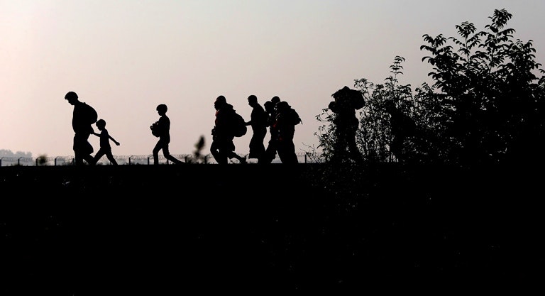 Migrants walk along the railway track after crossing the border between Serbia and Hungary on Sept. 13, 2015. (AP/Matthias Schrader)