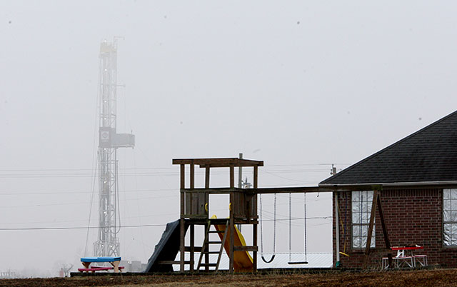 A natural gas drilling rig, left, on an empty field near a housing development in Guy, Arkansas, January 24, 2011. (Photo: Stephen Thornton / The New York Times)