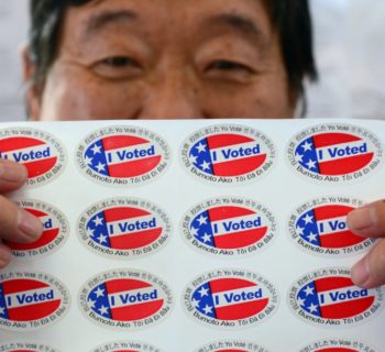 Election official Henry Tung displays a sheet of "I Voted" stickers in various  languages at a polling station at St. Paul's Lutheran Church in Monterey Park, Los Angeles County, on November 6, 2012 in California, as Americans flock to the polls nationwide to decide between President Barack Obama, his Rebuplican challenger Mitt Romney, and a wide range of other issues. Monterey Park is one of six cities in California's 49th Assembly District, the state's first legislative district where Asian-Americans make up the majority of the population.     AFP PHOTO/Frederic J. BROWN        (Photo credit should read FREDERIC J. BROWN/AFP/Getty Images)