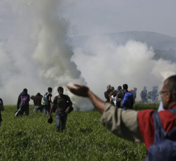 A group of migrant men run away from tear gas used by Macedonian police after migrants broke a fence at the northern Greek border point of Idomeni, Greece, Sunday, April 10, 2016. Thousands of migrants protested at the border and clashed with Macedonian police. (AP Photo/Amel Emric)