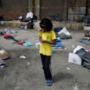 A refugee girl walks among belongings left behind by refugees and migrants that were transferred from a makeshift camp at the port of Piraeus to a newly built relocation centre at the port town of Skaramagkas, in western Athens, Greece April 11, 2016. REUTERS/Alkis Konstantinidis - RTX29FY0