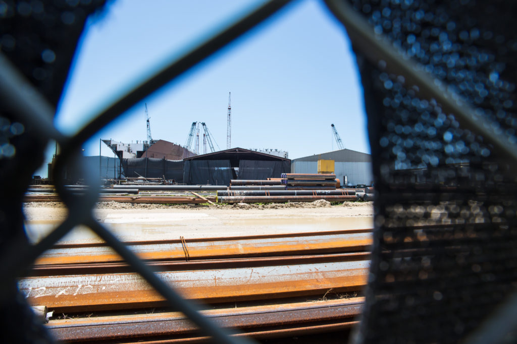 VT Halter Marine’s Pascagoula, Mississippi, shipyard, seen through a hole in fencing fabric.Credit: Julie Dermansky for Reveal