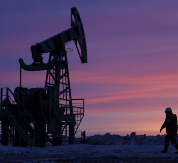 A worker walks past a pump jack on an oil field owned by Bashneft in Bashkortostan, Russia, January 28, 2015.      REUTERS/Sergei Karpukhin/File Photo