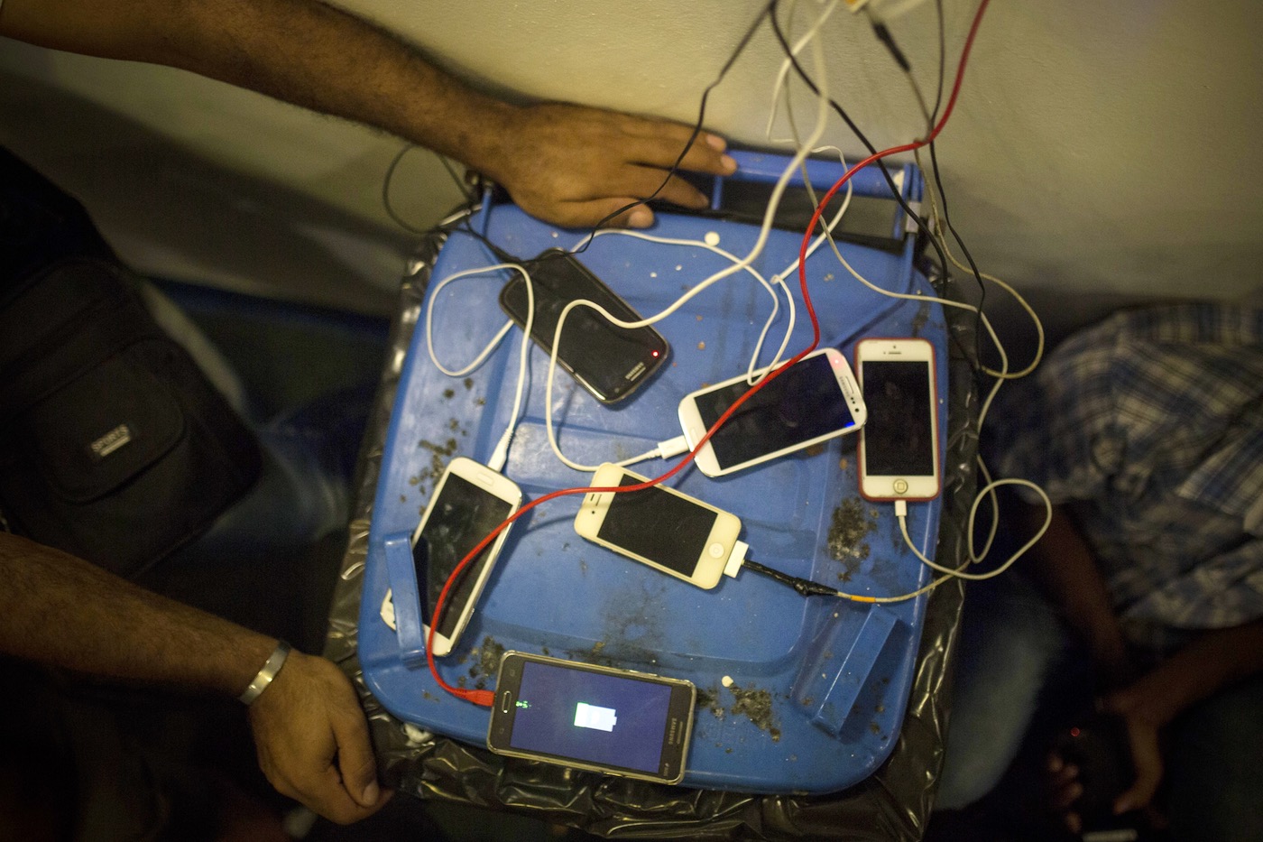 Refugees and migrants recharge the batteries on their cellphones on board a ferry from Lesbos to Athens, September 9, 2015. (AP/Santi Palacios)
