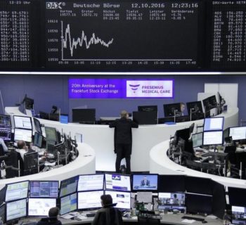 Traders work at their desks in front of the German share price index, DAX board, at the stock exchange in Frankfurt, Germany, October 12, 2016. REUTERS/Staff/Remote