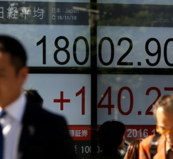 People walk past an electronic board showing Japan's Nikkei average outside a brokerage in Tokyo, Japan, November 18, 2016.   REUTERS/Toru Hanai