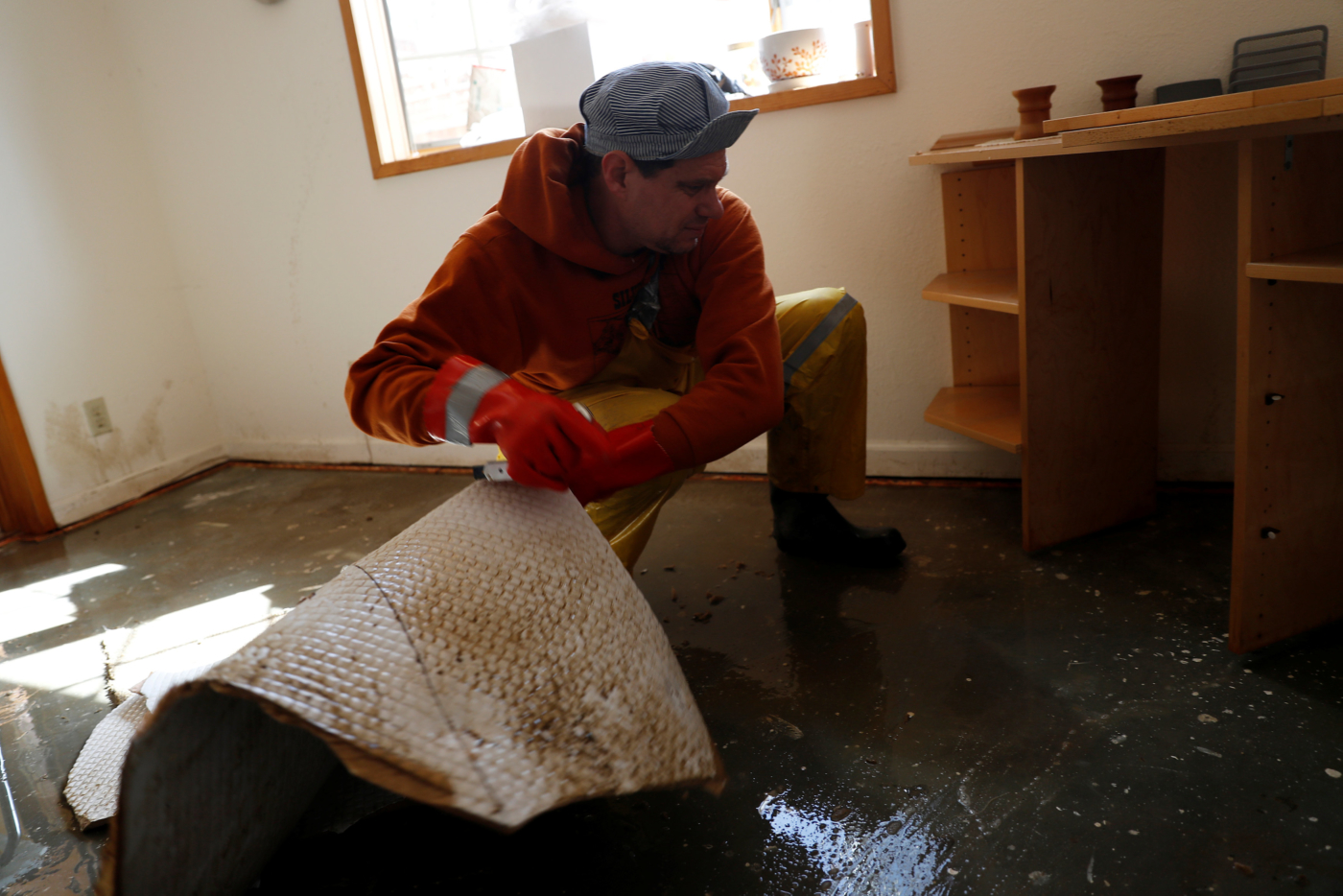 Wil Henninger cuts a carpet soaked in flood water inside the home of neighbor Judy Georges after an overflowed Coyote Creek flooded neighborhoods and prompted an evacuation in San Jose, California, U.S., February 22, 2017. REUTERS/Stephen Lam
