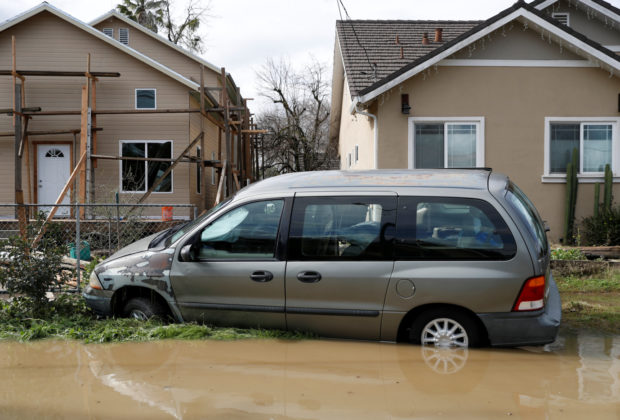 A car is see partially submerged in water after Coyote Creek burst its banks and flooded nearby neighborhoods and prompted evacuation of more than 14,000 residents in San Jose, California, U.S., February 22, 2017. REUTERS/Stephen Lam