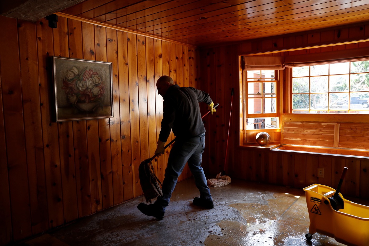 Alessio Roic mops up flood water inside the home of neighbor Judy Georges after an overflowed Coyote Creek flooded neighborhoods and prompted an evacuation in San Jose, California, U.S., February 22, 2017. REUTERS/Stephen Lam